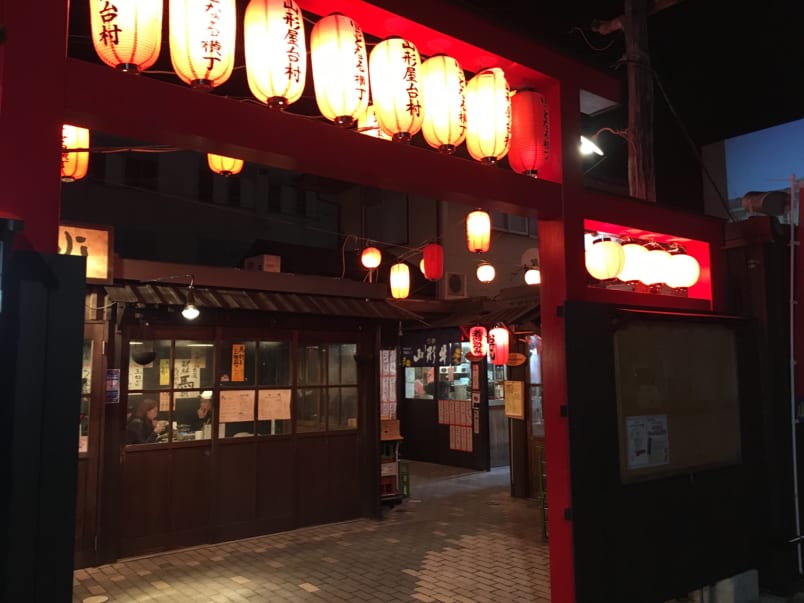 Yakitori restaurant and bar with brightly lit paper lanterns hanging in front