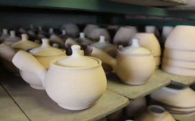 shelf full of pottery teapots