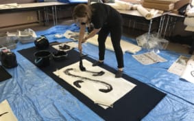 Woman doing calligraphy with a huge brush